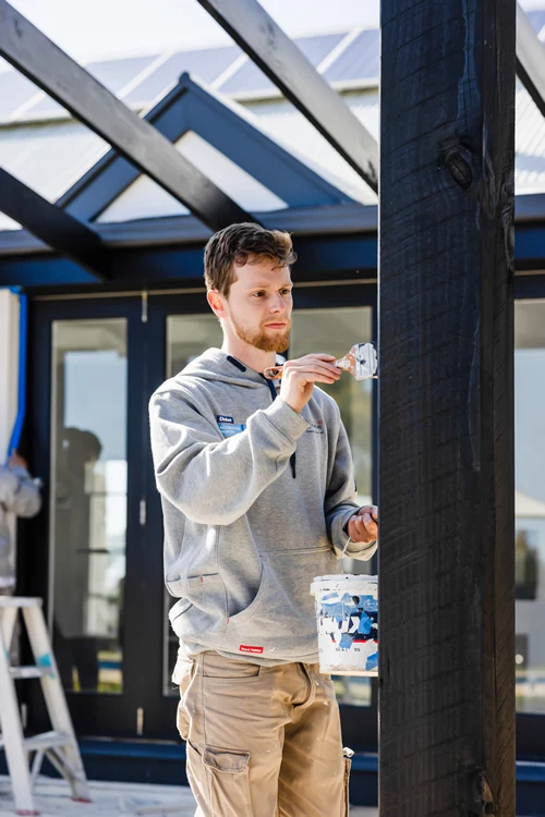 Painter paints veranda post at Adelaide house